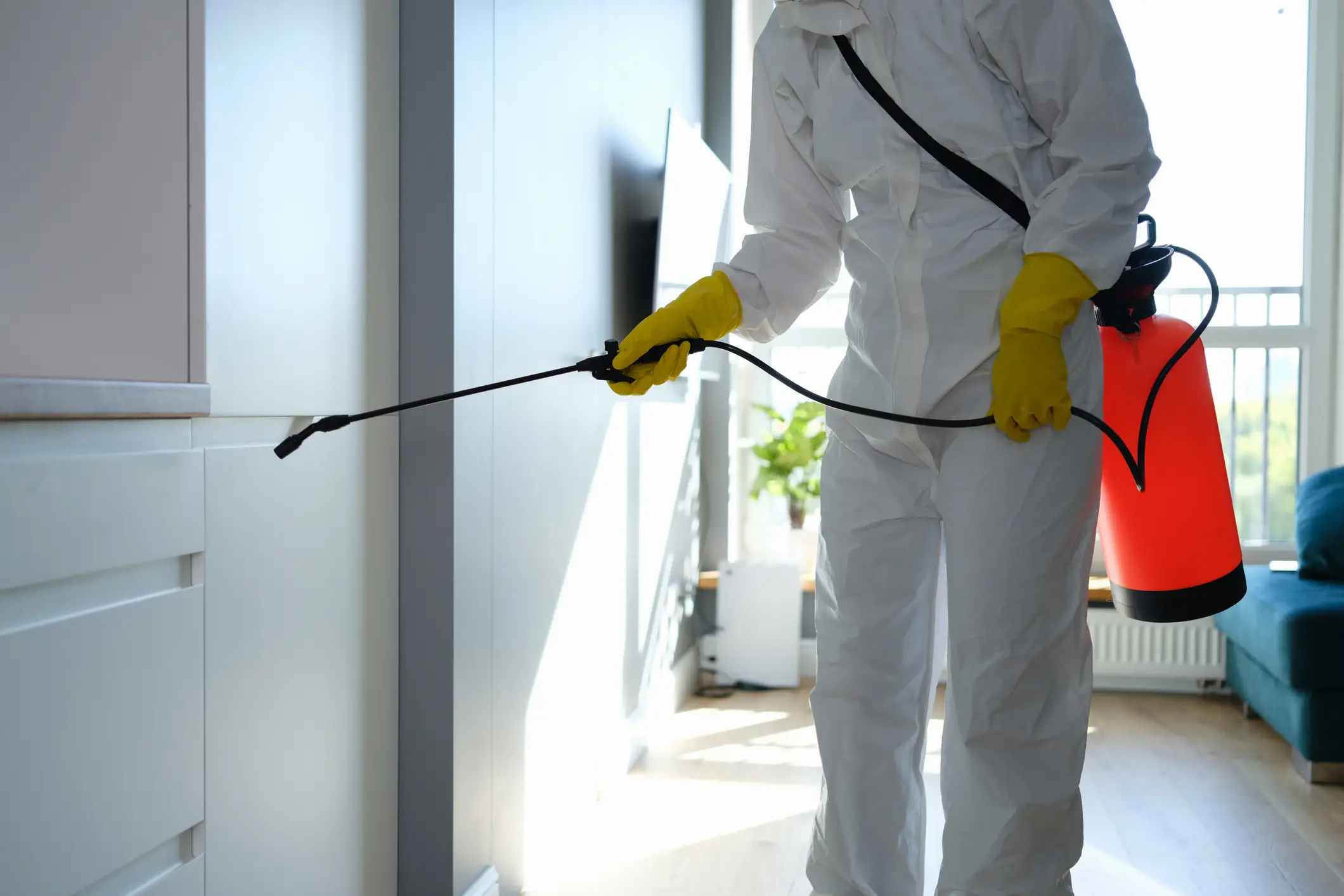 Person in hazmat suit spraying disinfectant.